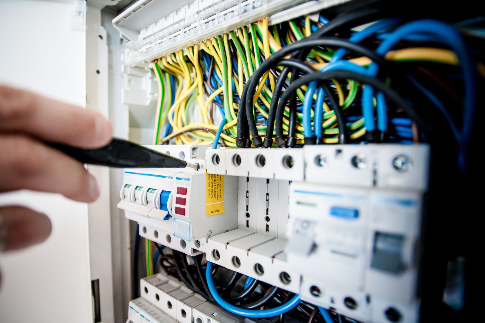 Electrician's hand working on a circuit breaker panel