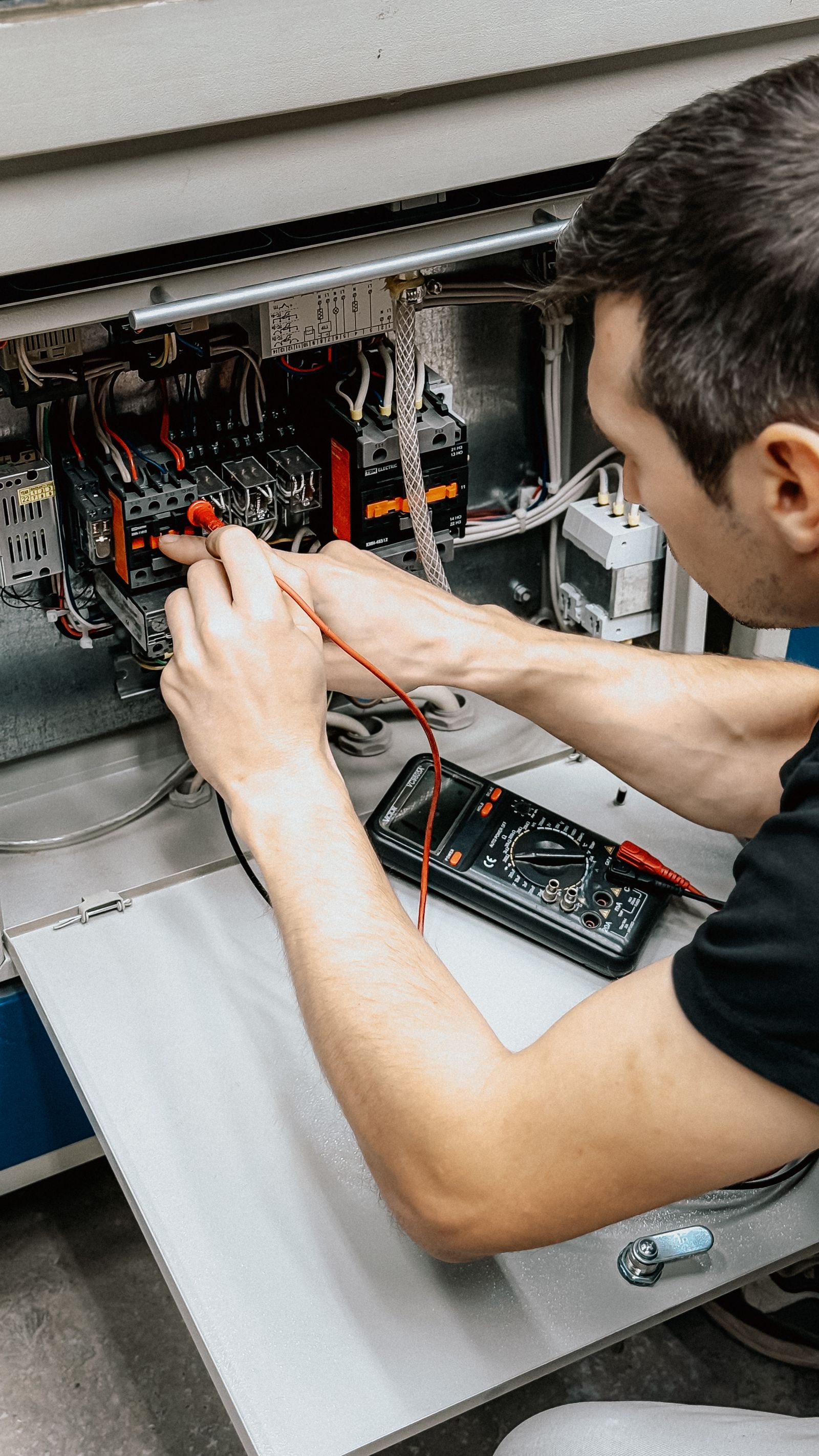 Electrician testing an electrical panel with a multimeter